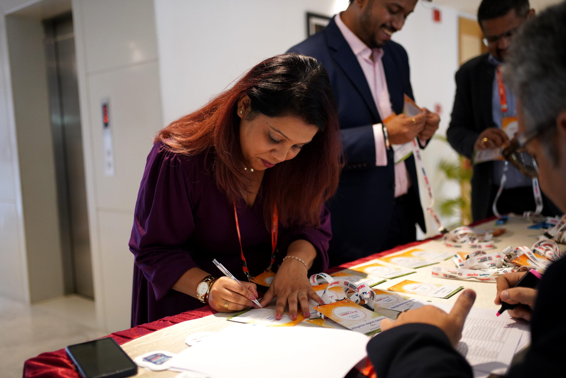 A delegate signing the registration sheet, name badges spread across the table
